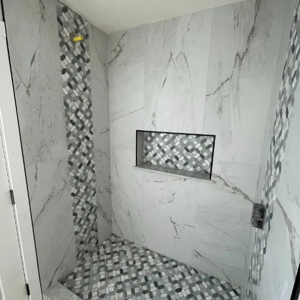 Elegant bathroom remodel by The Hanson Company, home remodeling experts, featuring marble and mosaic tile shower.